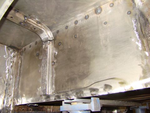 1948 Jeep Wrangler - The interior of a vehicle undergoing metal repair and welding, showing extensive work on the frame and panels.
