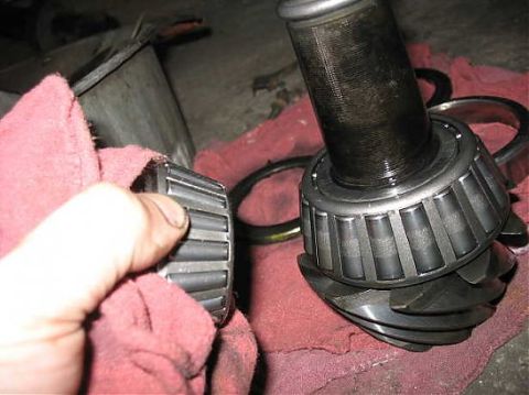 1995 Ford C-350 (Centurion Conversions) - A differential gear and bearing assembly is shown, with a hand holding a separate bearing in the foreground.