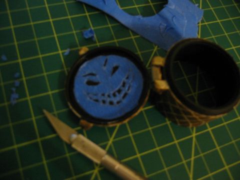 1996 Ford Bronco - A craft knife is positioned near a circular object with a smiley face pattern cut into blue tape.