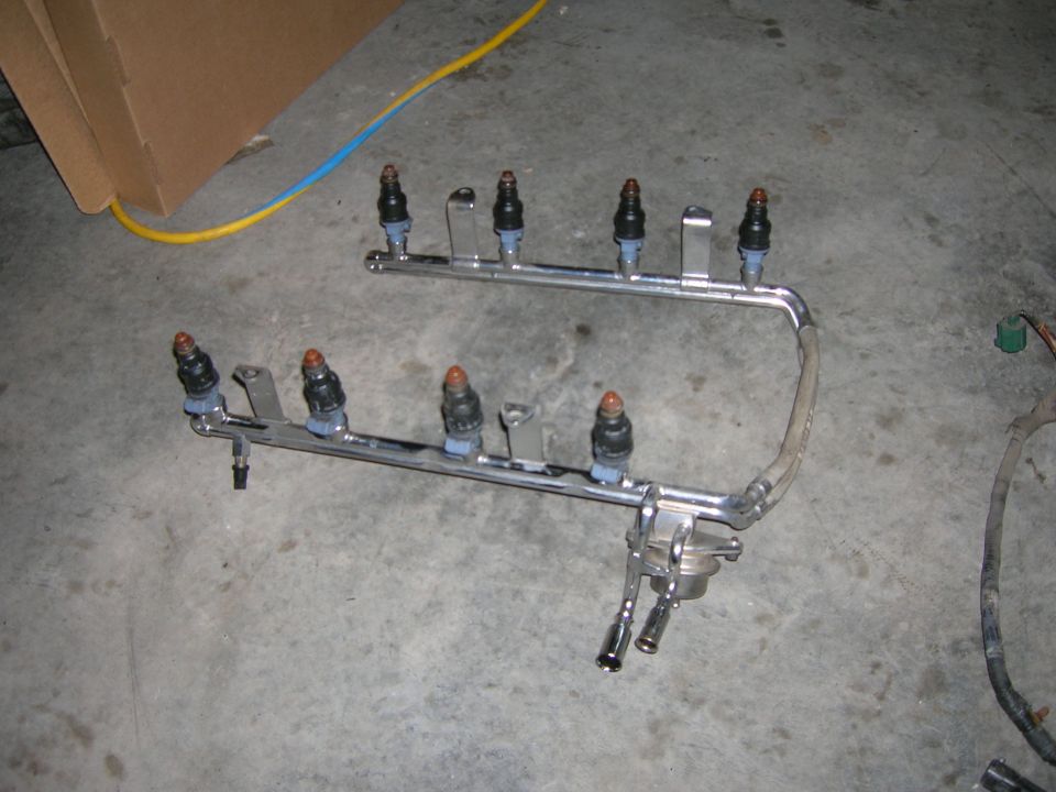 Pair of chrome fuel rails with eight fuel injectors on a floor