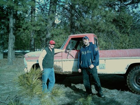 1968 Ford F-250 - A red and white pickup truck is parked in a wooded area with two men standing beside it.