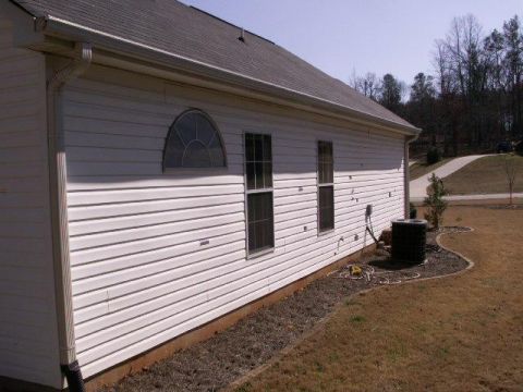 1995 Ford F-150 - The side of a house is shown with vinyl siding, windows, and an air conditioning unit in the yard.