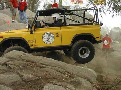 1997 Ford Ranger - An off-road vehicle navigates a rocky terrain during an event, with spectators watching.