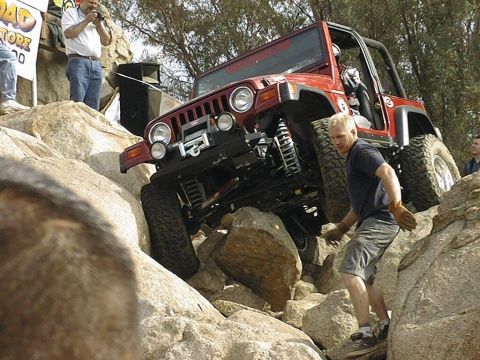 1997 Ford Ranger - A man guides a red Jeep Wrangler over large rocks during an off-road event.