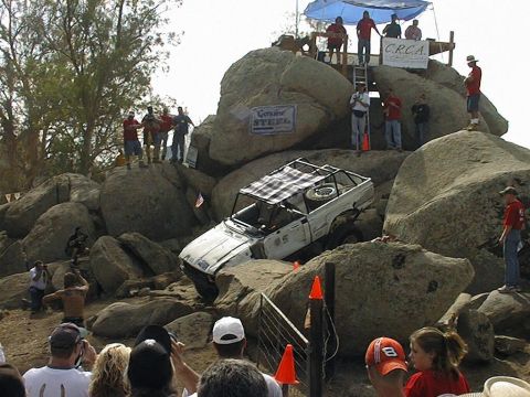 1997 Ford Ranger - A modified off-road vehicle navigates a challenging rocky terrain during an event, with spectators observing from the sidelines.