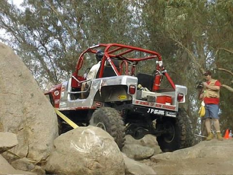 1997 Ford Ranger - An off-road vehicle with a custom roll cage is shown maneuvering through a rocky terrain.