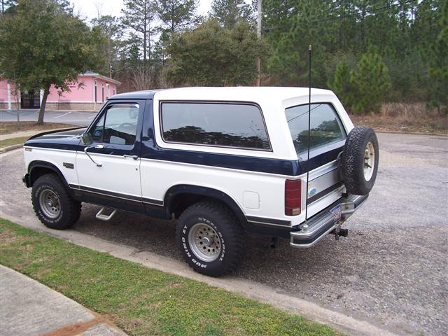1980s Ford Bronco full-size SUV in two-tone navy and white parked on gravel