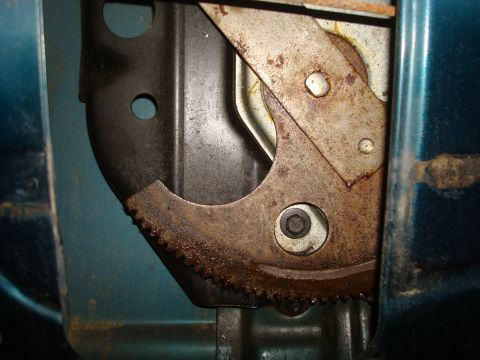 1995 Ford Bronco - Close-up of a rusty window regulator mechanism, with teal paint on the exterior panel.