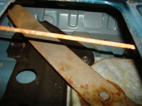 1995 Ford Bronco - Close-up of a rusty tailgate window regulator mechanism, showing internal components and the blue interior of the vehicle.