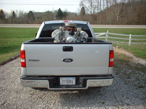 1970 Ford Mustang - Rear view of a silver Ford F-150 pickup truck carrying a V8 engine in its bed.