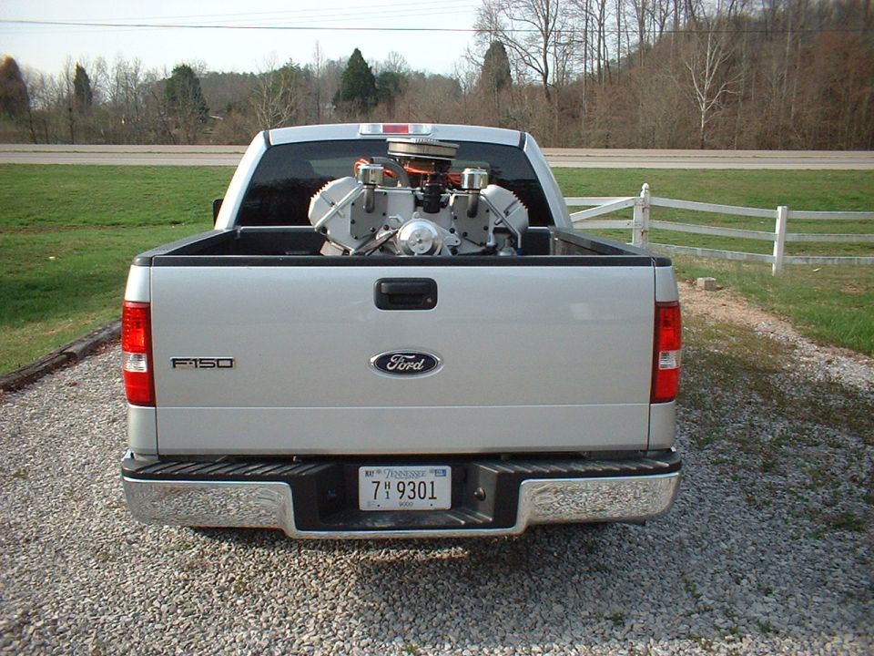 Silver Ford F-150 pickup truck rear view with a V8 engine in the bed