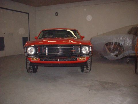 1970 Ford Mustang - Front view of a red 1970 Ford Mustang parked indoors next to a covered vehicle.
