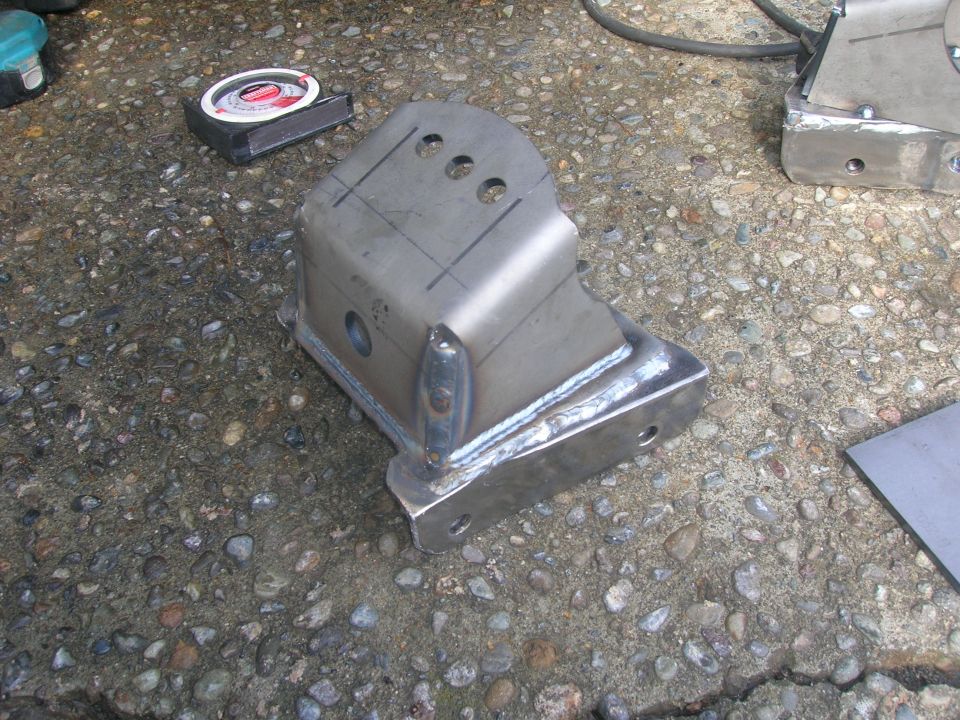 Fabricated metal bracket with three holes on top and welded seams