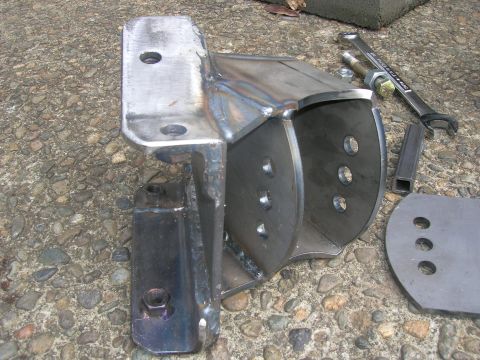1996 Ford Bronco - A fabricated metal bracket, likely for vehicle suspension, sits on the ground with tools nearby.