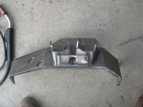 1996 Ford Bronco - A custom-fabricated metal bracket, likely for a suspension component, is shown on a concrete surface next to a welding gun. The bracket is…