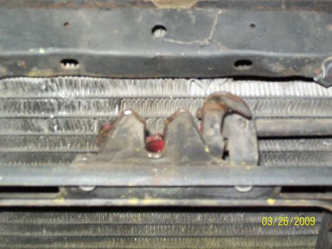 1973 Mercury Cougar - Close-up of a vehicle's hood latch mechanism and radiator, with visible rust and wear.