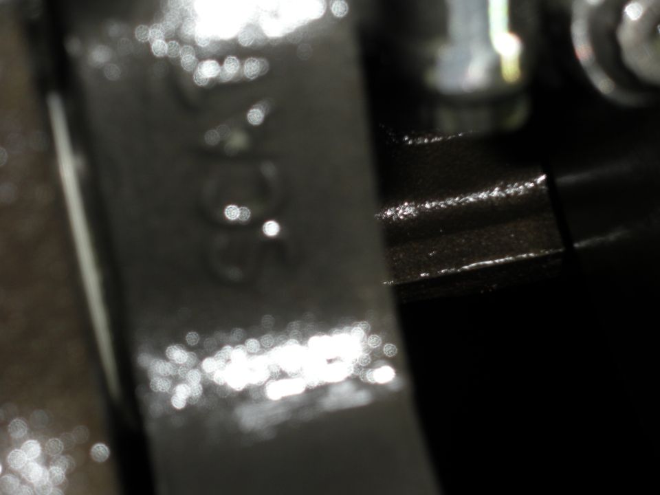 Close-up of a dark metal engine part with some blurry numbers stamped on it