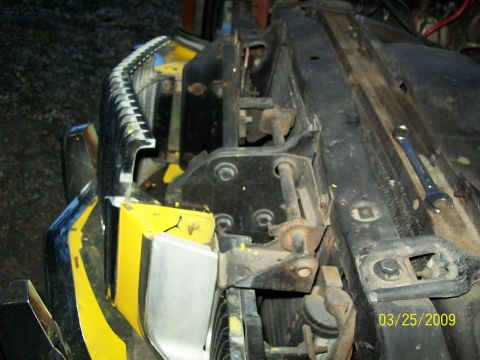 1973 Mercury Cougar - Close-up of a vehicle's hood latch assembly, showing mechanical components and yellow and black paint markings.