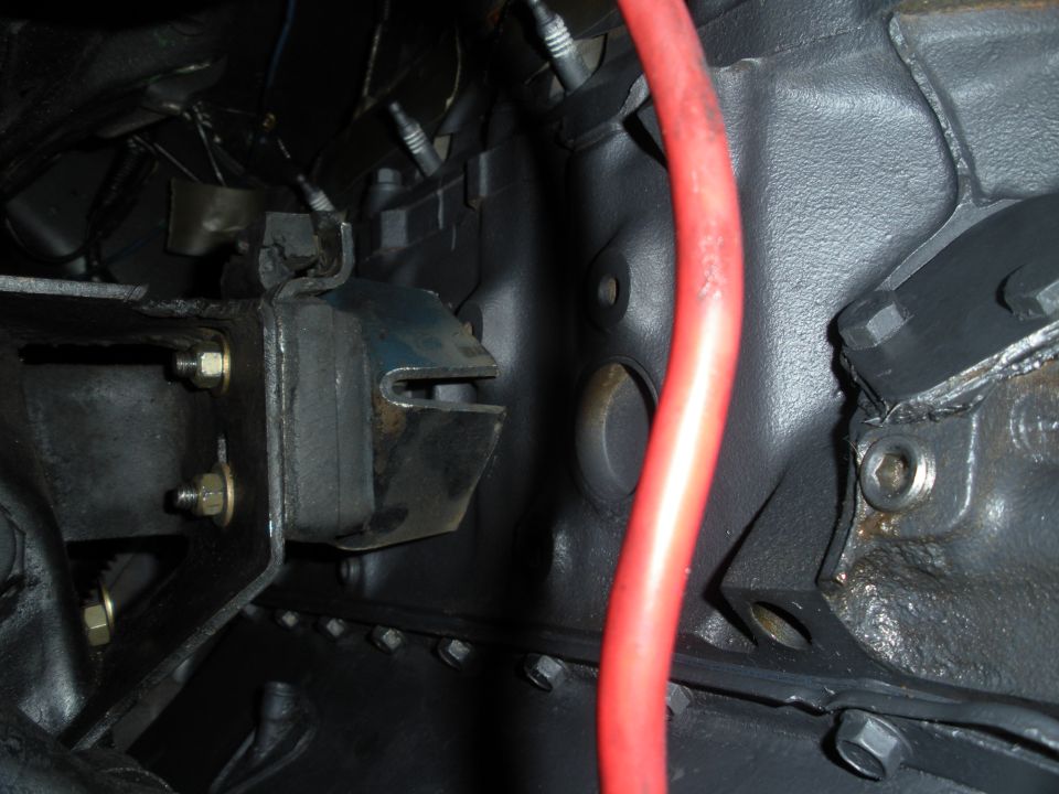 Close-up of a vehicle's engine mount with a red hose nearby