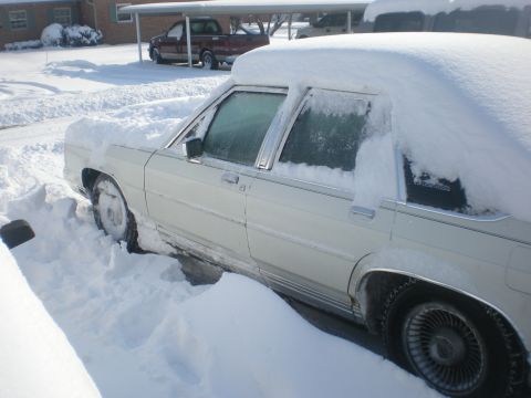 1988 Ford Crown Victoria LTD - White 1988 Ford Crown Victoria LTD buried in snow, with a truck parked nearby under a carport.