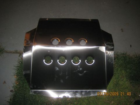 1909 Ford Bronco - A shiny metal skid plate with multiple circular openings is shown outdoors.