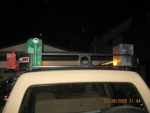 1909 Ford Bronco - A vehicle's roof rack is loaded with a jerry can and a metal storage box, captured at night.