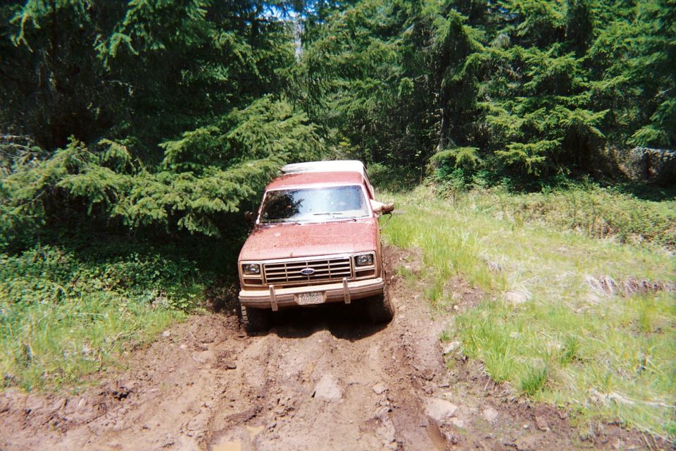 Red 1980s Ford Bronco on muddy trail