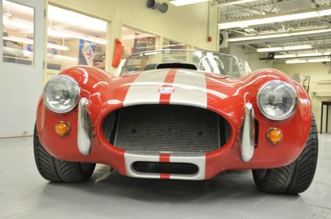 1996 Ford Bronco - Front view of a red Shelby Cobra replica with dual silver racing stripes and a prominent grille.