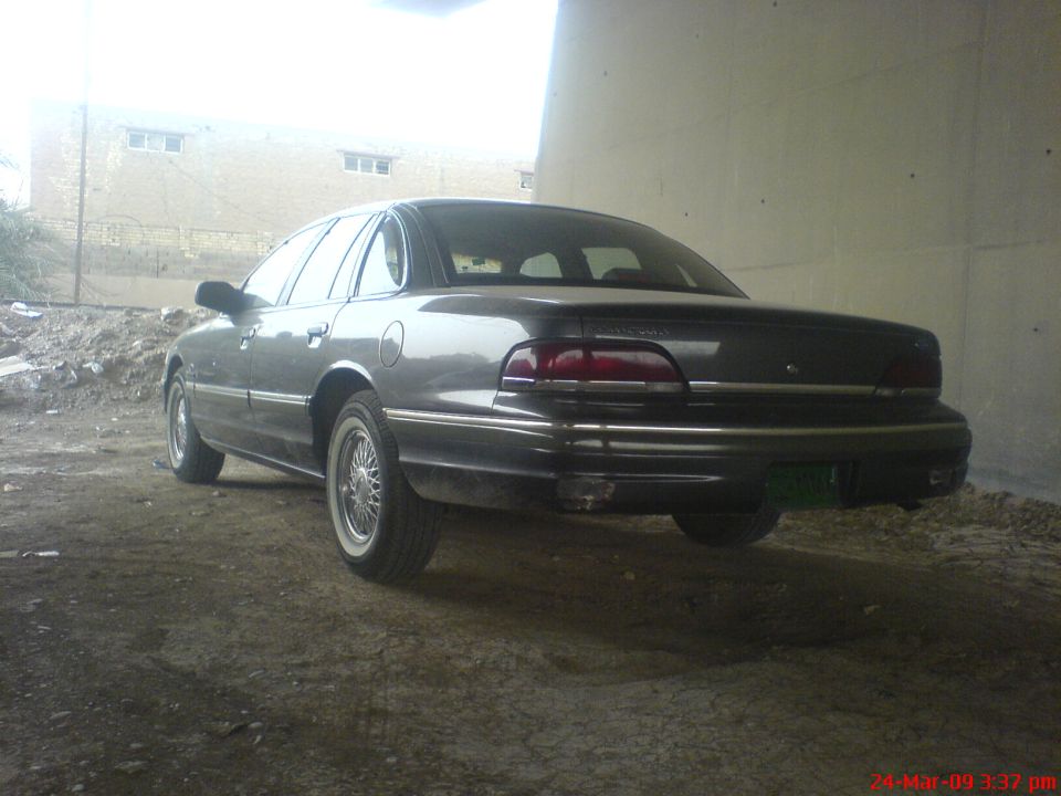 Dark gray Ford Crown Victoria sedan rear 3/4 view with whitewalls and wire wheel covers
