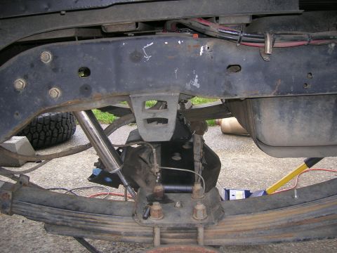 1996 Ford Bronco - Close-up view of a vehicle's rear suspension components, including leaf springs, a shock absorber, and the fuel tank.