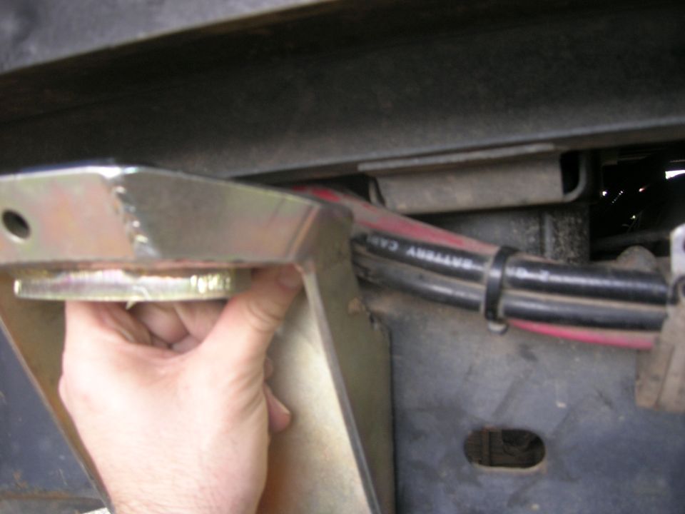 Metal bracket attached to vehicle frame with red and black battery cables