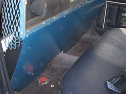 1991 Ford LTD Crown Victoria - The interior of a vehicle shows a blue partition and metal cage, likely for a police car or transport vehicle.