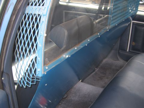 1991 Ford LTD Crown Victoria - The interior of a police car shows a partition with a blue metal grate.