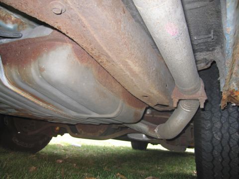 1991 Ford LTD Crown Victoria - The undercarriage of a vehicle displays significant rust on the frame and exhaust components.