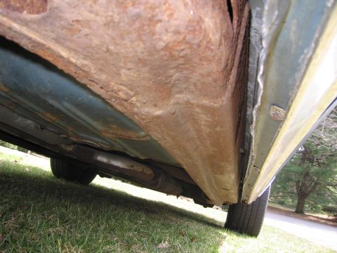 1991 Ford LTD Crown Victoria - The undercarriage of a car displays extensive rust damage on its frame and rocker panels.