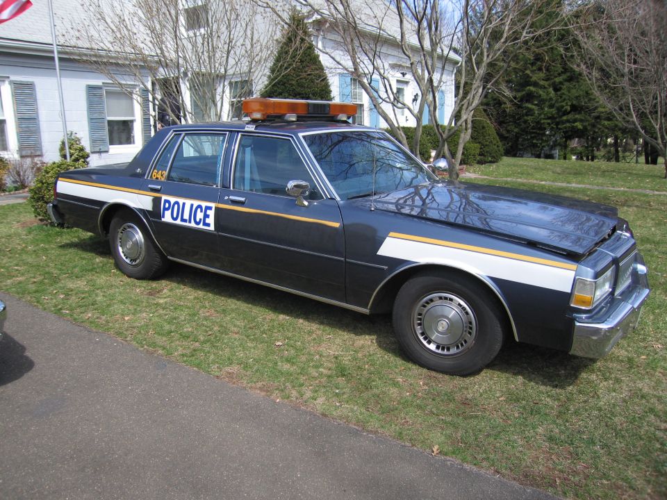 Dark blue police car with "POLICE" text and light bar