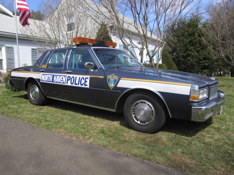 1991 Ford LTD Crown Victoria - A dark blue police car with "NORTH HAVEN POLICE" text is parked on a grassy lawn in front of a house.