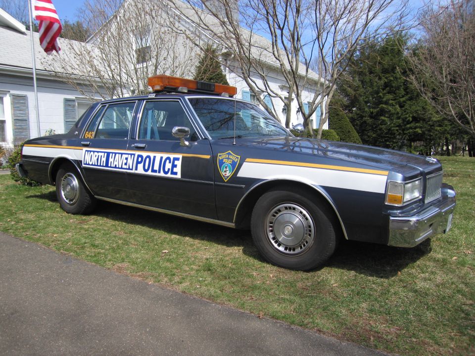 Dark blue police car with white and yellow stripe, "NORTH HAVEN POLICE" text, and light bar