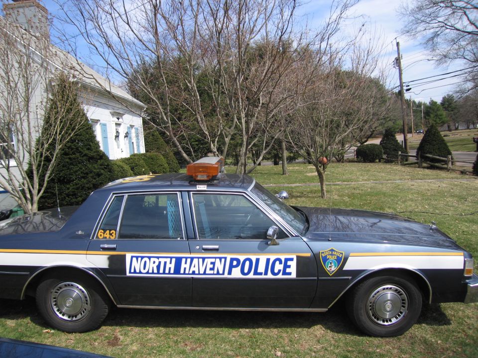 Side view of a dark blue and white police car with 'NORTH HAVEN POLICE' on the door and a light bar on the roof