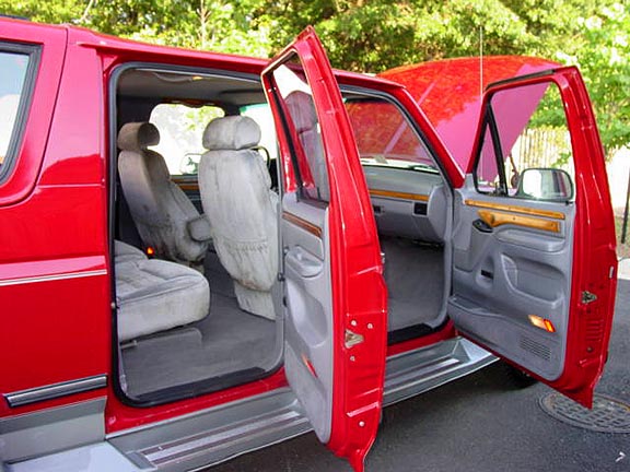Red SUV interior with open door showing gray cloth seats and woodgrain door trim