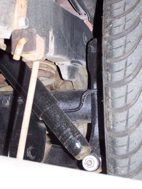 1973 Ford Ranchero - A close-up view of a vehicle's rear suspension component, showing a shock absorber with visible text and a portion of the tire.