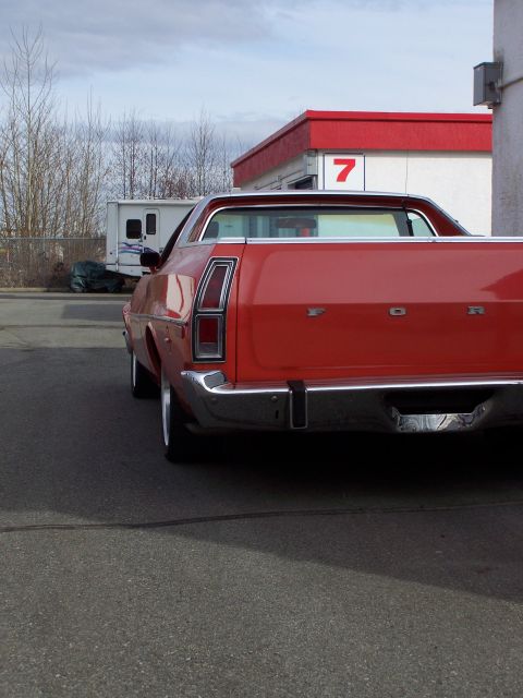 1973 Ford Ranchero - Low rear three-quarter view of a red Ford Ranchero showing the vertical chrome-trimmed taillight, FORD block lettering across the tailgate…