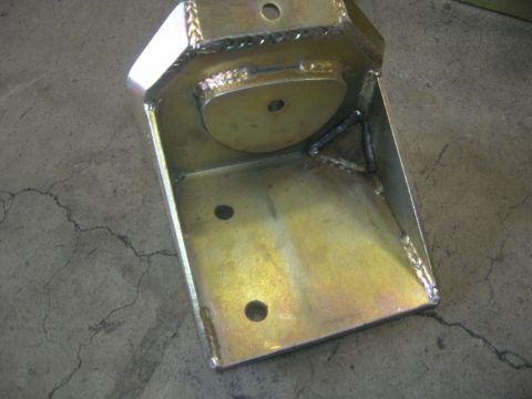1996 Ford Bronco - A custom-fabricated metal bracket, likely for automotive suspension, sits on a concrete floor.