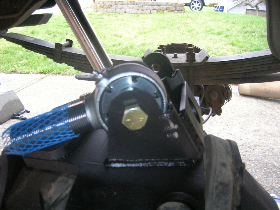 Close-up of a black suspension component with a blue mesh cover and a large bolt