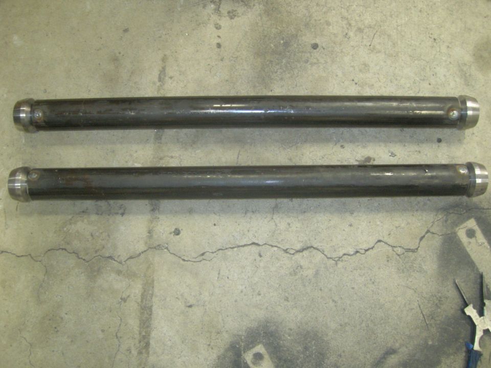 Two dark metal suspension rods with silver caps on a concrete floor