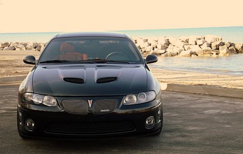1998 Ford Taurus - A black Pontiac GTO is parked near a rocky shoreline with the ocean in the background.