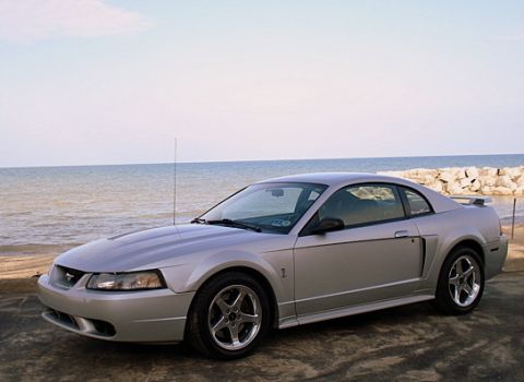 1998 Ford Taurus - This silver coupe, likely a 1999 model, is parked near a rocky shoreline.