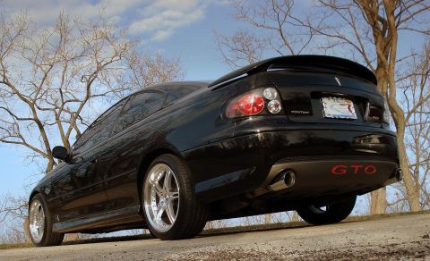 1998 Ford Taurus - Rear view of a black Pontiac GTO with red GTO badging on the lower bumper.