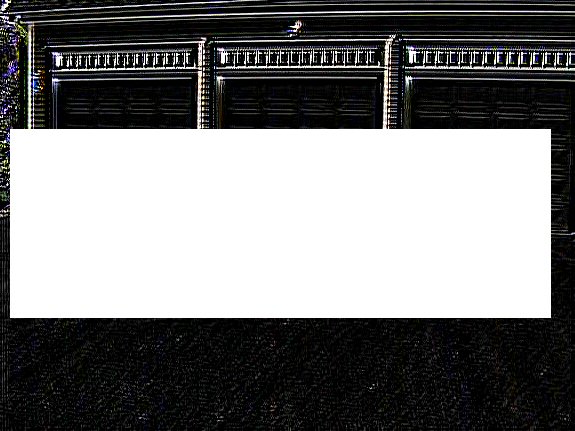 Black garage door with three panels and decorative trim above a white rectangle