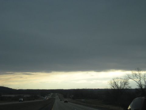 1978 Ford Bronco - A highway stretches into the distance under a heavy, dark cloud cover, with other vehicles visible on the road.